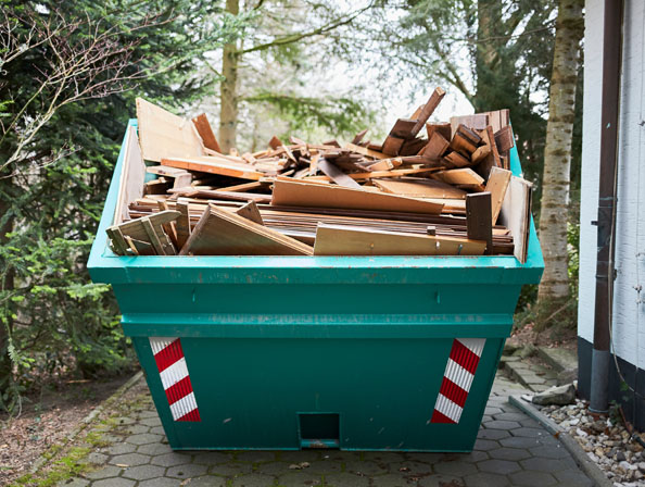 Entrümpelung Essen – Holzcontainer beladen Grüner Abfallcontainer gefüllt mit Holzplanken und Brettern