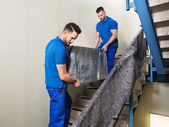 Möbeltransport sicher die Treppe hinunter – Haushaltsauflösung Essen Zwei Umzugshelfer tragen schweren Schrank die Treppe hinunter bei einer Haushaltsauflösung in Essen