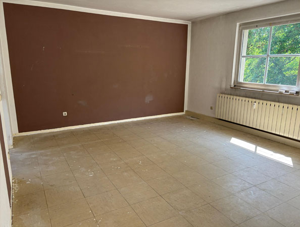 Wohnungsauflösung Essen zum Festpreis Leergeräumtes Zimmer mit brauner Akzentwand und großen Fenstern