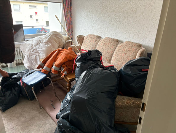 Festpreis-Entrümpelung – Wohnungsräumung Wohnbereich mit Couch und mehreren Müllsäcken bei Räumungsvorbereitung