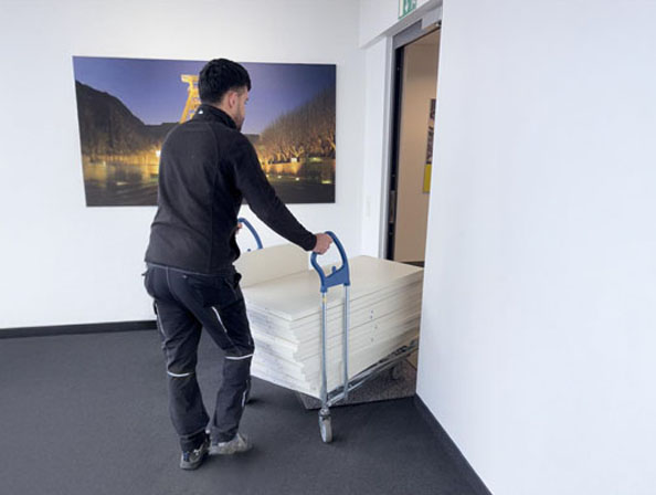 Mobiliarentsorgung bei Firmenauflösung in Essen Handwerker transportiert zerlegte Schreibtischplatten auf Rollwagen